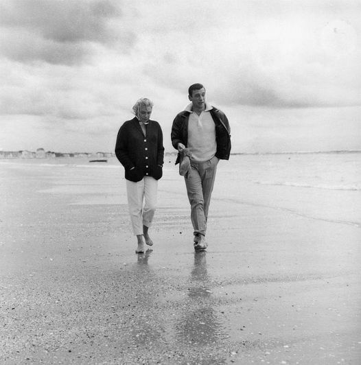 Η Simone Signoret και ο σύζυγός της Yves Montand περπατούν κατά μήκος της παραλίας στο La Baule.... 1