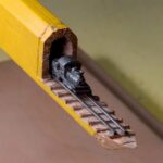 Ένα τρένο από σκαλισμένο γραφίτη σε ράγες αναδύεται μέσα από το μολύβι ενός ξυλουργού...
