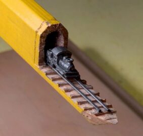 Ένα τρένο από σκαλισμένο γραφίτη σε ράγες αναδύεται μέσα από το μολύβι ενός ξυλουργού...