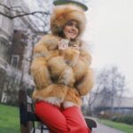 Η Olivia Newton-John φορώντας ένα βαρύ γούνινο παλτό έξω από το ξενοδοχείο Savoy στο Λονδίνο, 1...