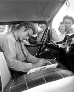 Ο Τζέιμς Ντιν κάθεται σε ένα αυτοκίνητο, υπογράφοντας φωτογραφίες για τους θαυμαστές του στο απόγειο της φροντίδας του...
